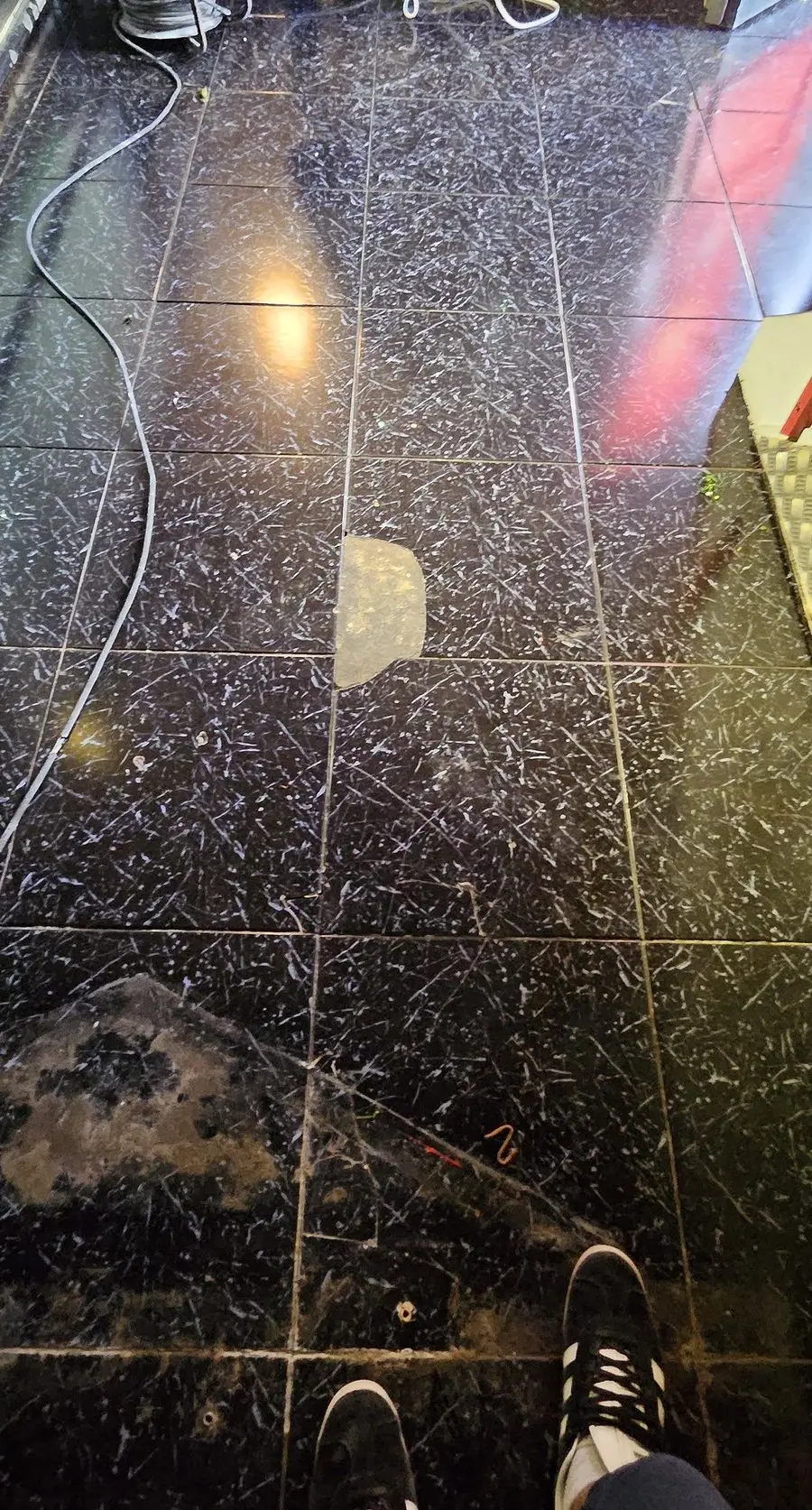 Le sol existant avant travaux : carrelage foncé rayé, taché et réparé par endroits.