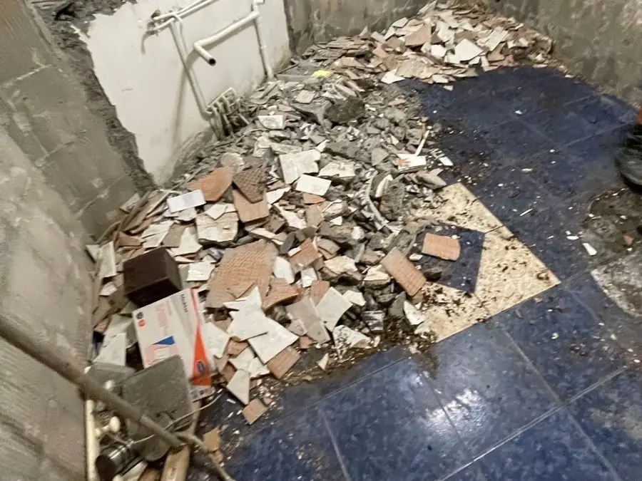 Ancienne salle de bain à Rivière des Pluies : sol carrelé bleu et faïence en cours de dépose, gravats au sol.