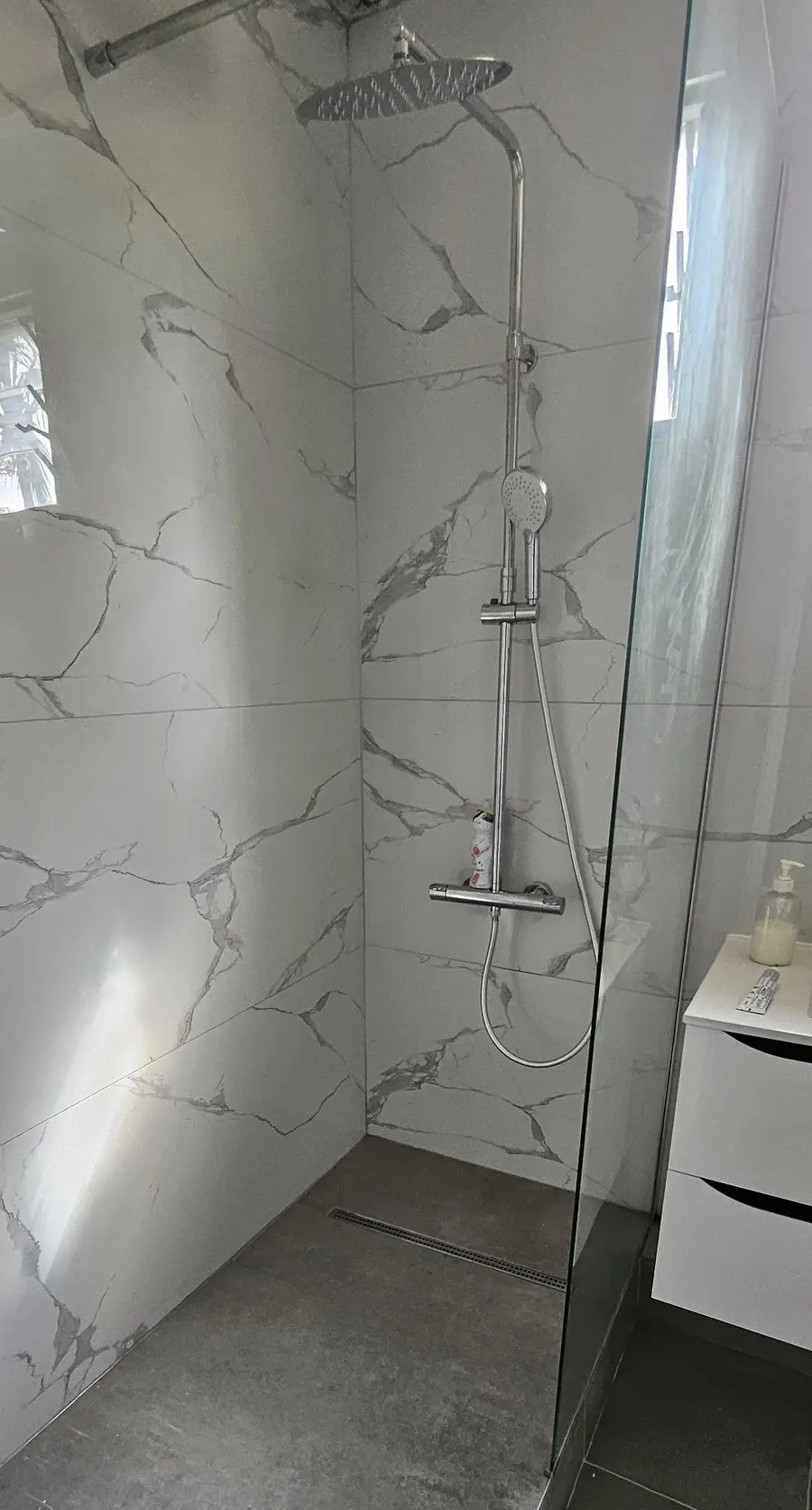 La même douche après travaux : douche à l’italienne et carrelage grand format effet marbre.