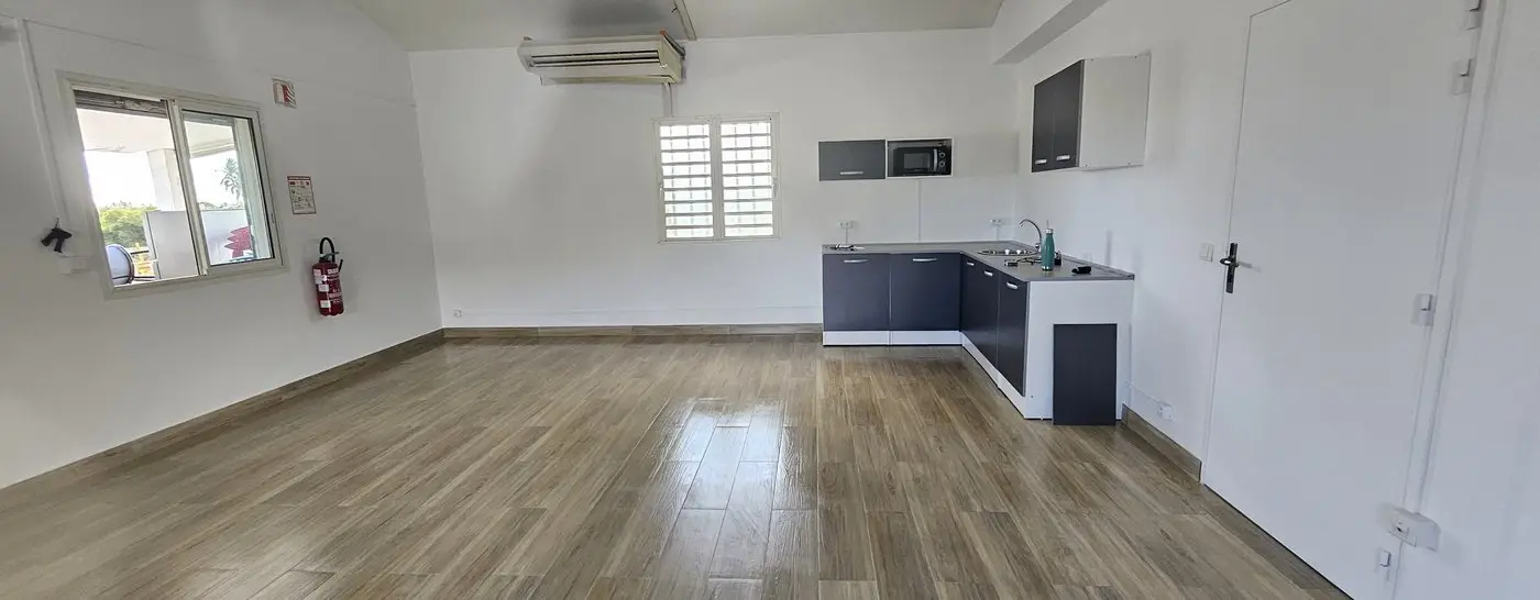 La même salle après travaux : carrelage grand format effet bois, murs repeints et cuisine équipée.