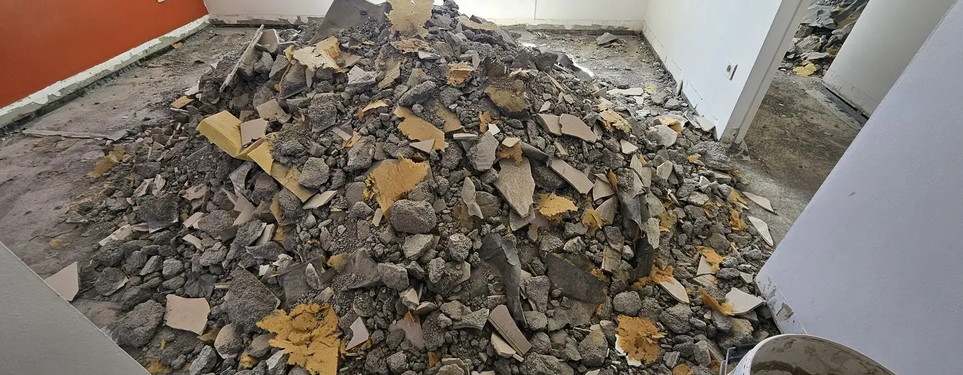 Sol déposé à Saint-Denis : tas de gravats, ancien carrelage et colle arrachés jusqu’au support.